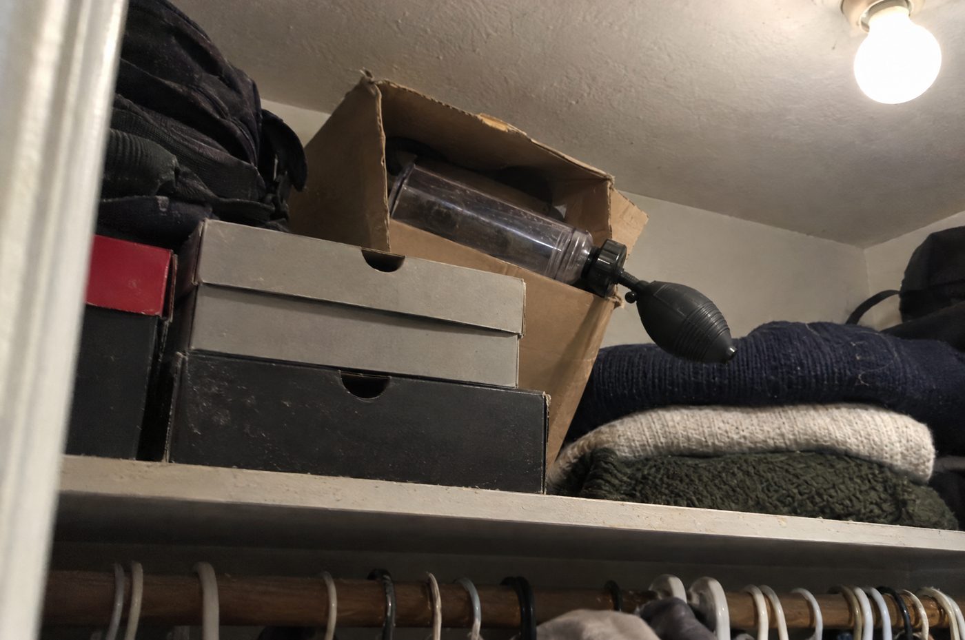 A dusty vacuum pump box shoved at the back of a closet shelf